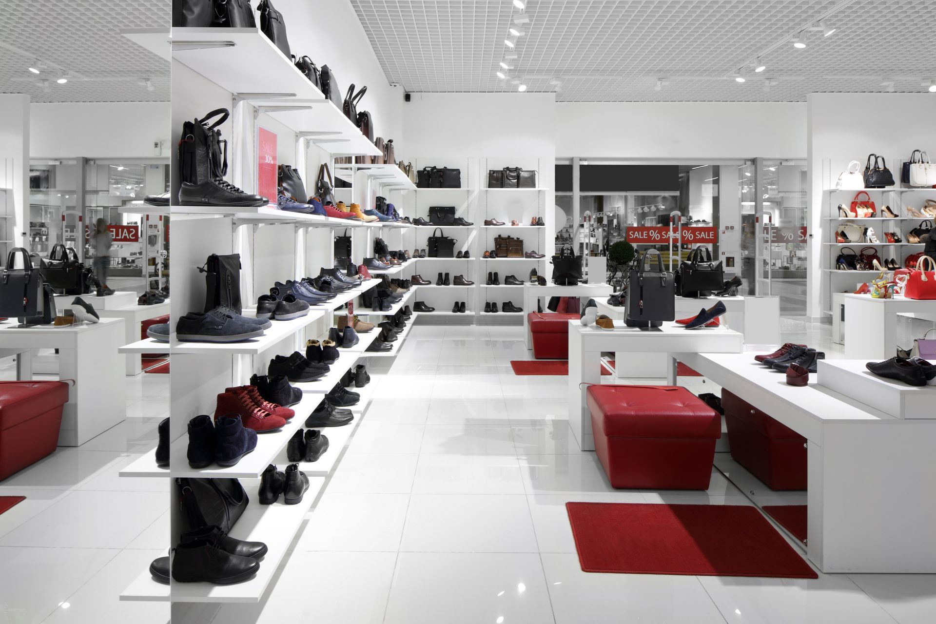 Shoe store interior: white walls, shelving displays shoes and bags, red accents.