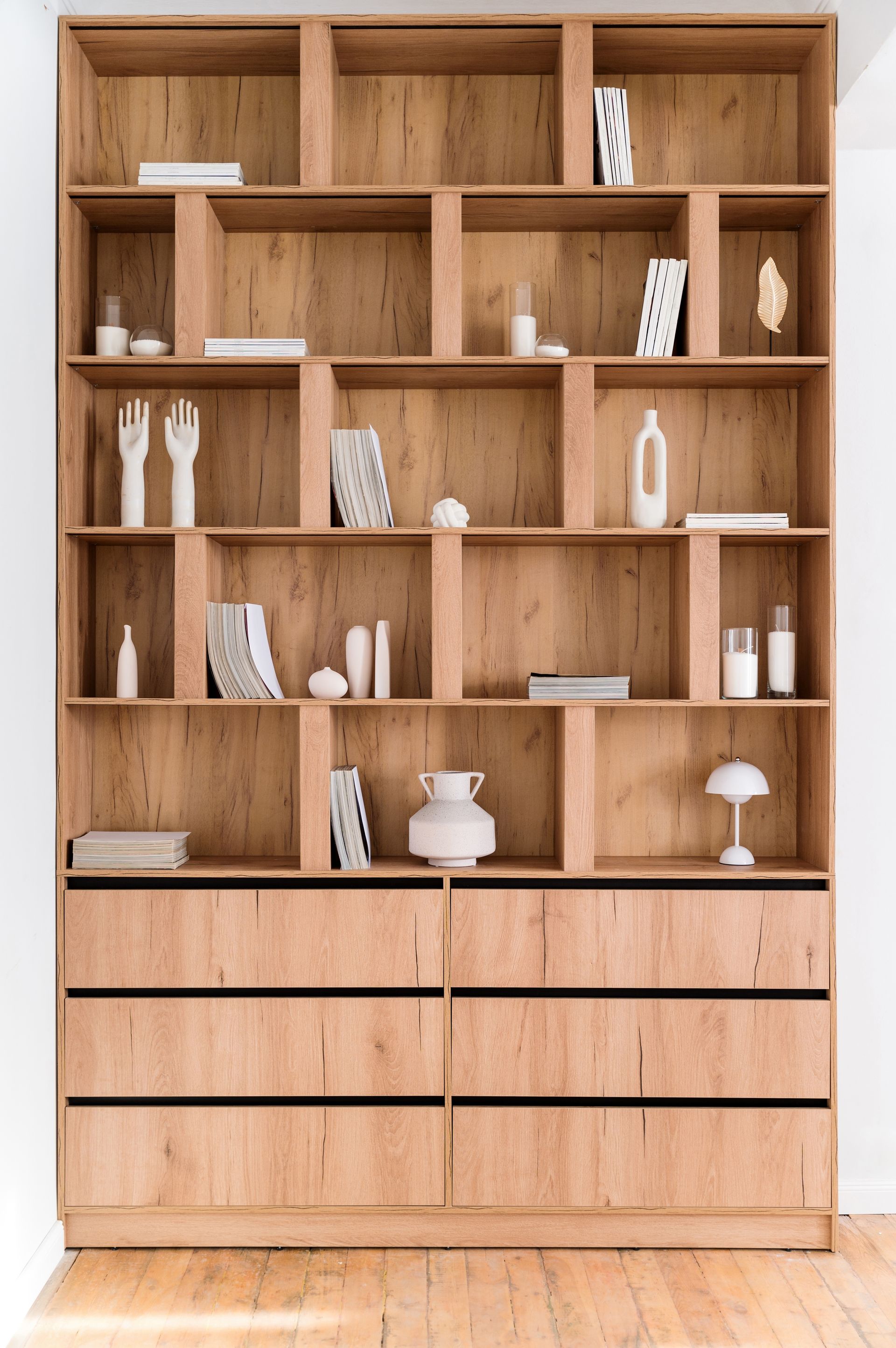 Wooden bookcase with various decorative objects displayed on shelves, against a white wall.