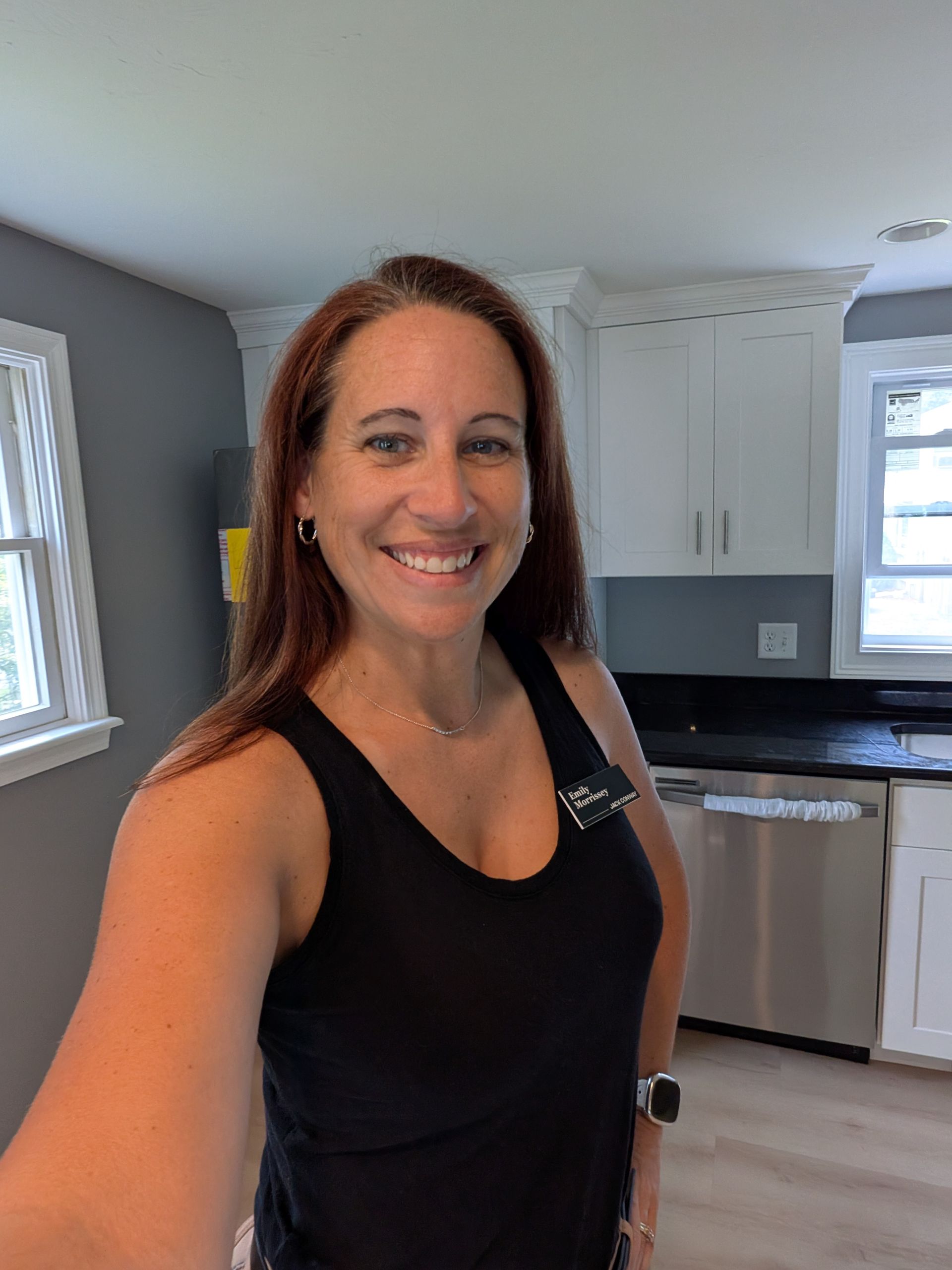 A woman is sitting at a desk with a laptop and a vase of flowers.