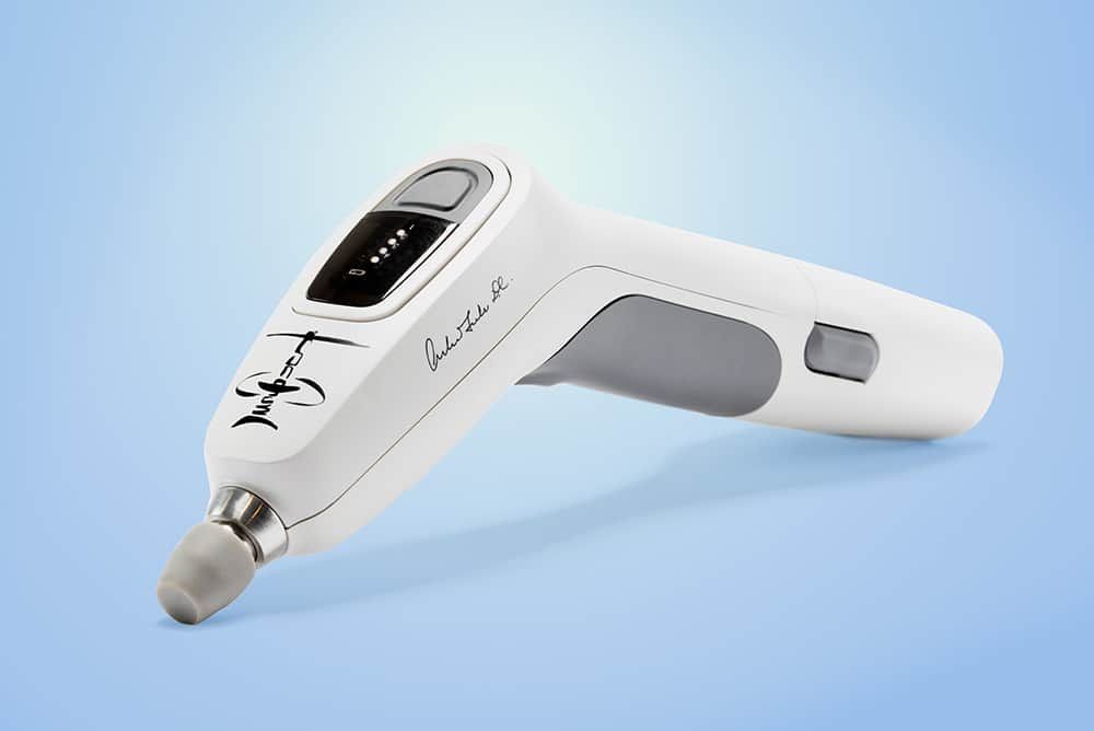 A white device with a gray handle is sitting on a blue surface.