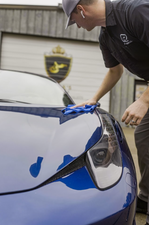 a man is cleaning a blue car with a cloth .