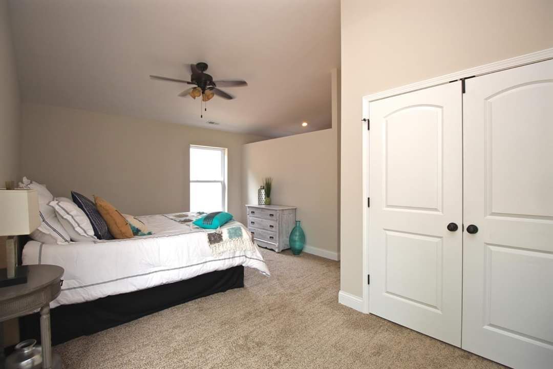 Bedroom with bed, closet, dresser, ceiling fan, and carpet. Neutral colors, natural light.