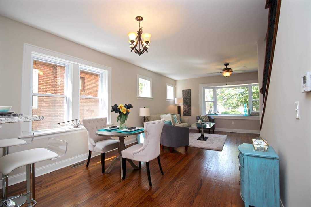 Living room with dining area, hardwood floors, chandelier, and a stairway.