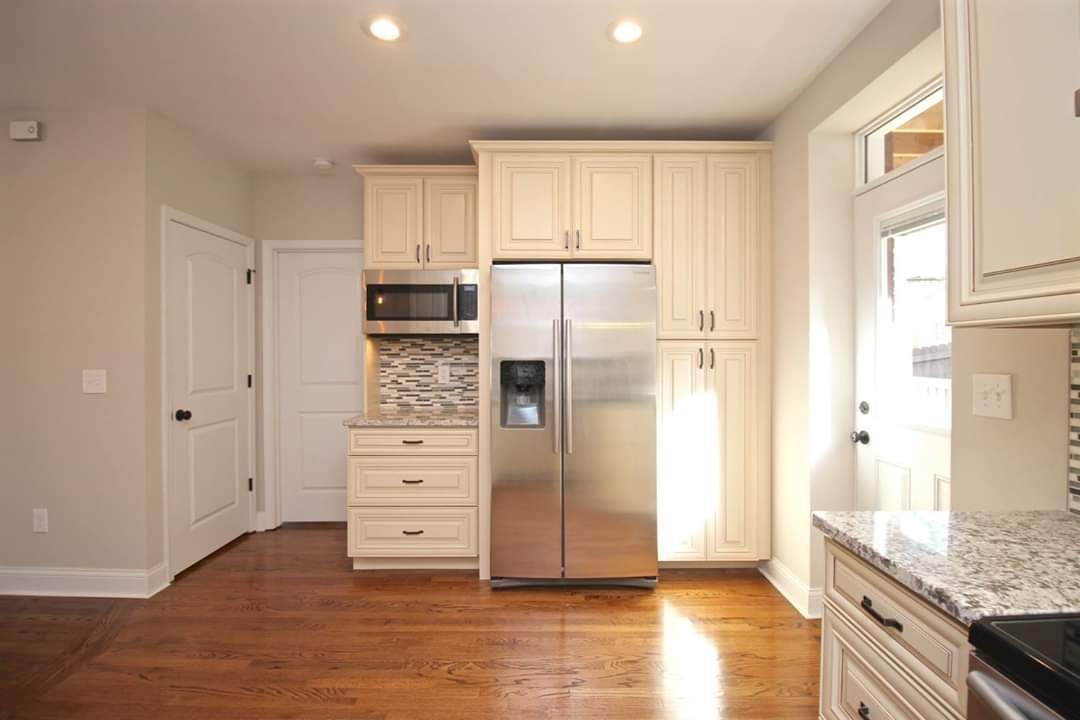 Kitchen with light cabinets, stainless steel refrigerator, and hardwood floors.