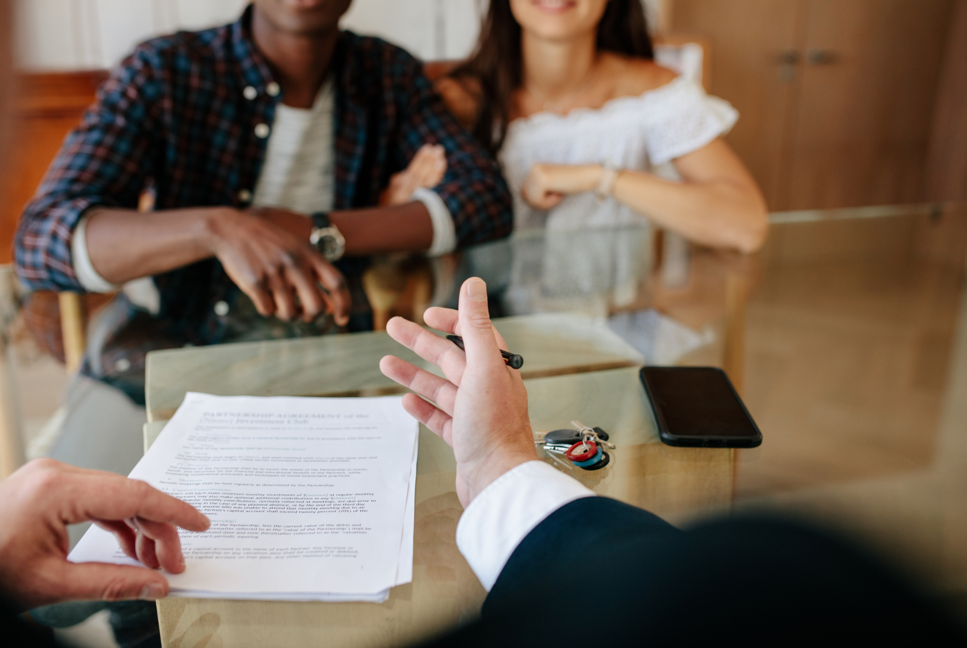 Real estate agent showing paperwork to a couple, signing a contract in a home.