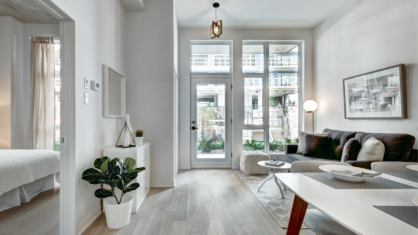 Bright, modern living room with large windows, neutral tones, and a view of a balcony.