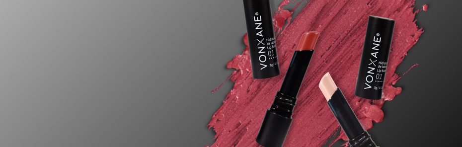 Tres lápices labiales están uno al lado del otro sobre una superficie gris.
