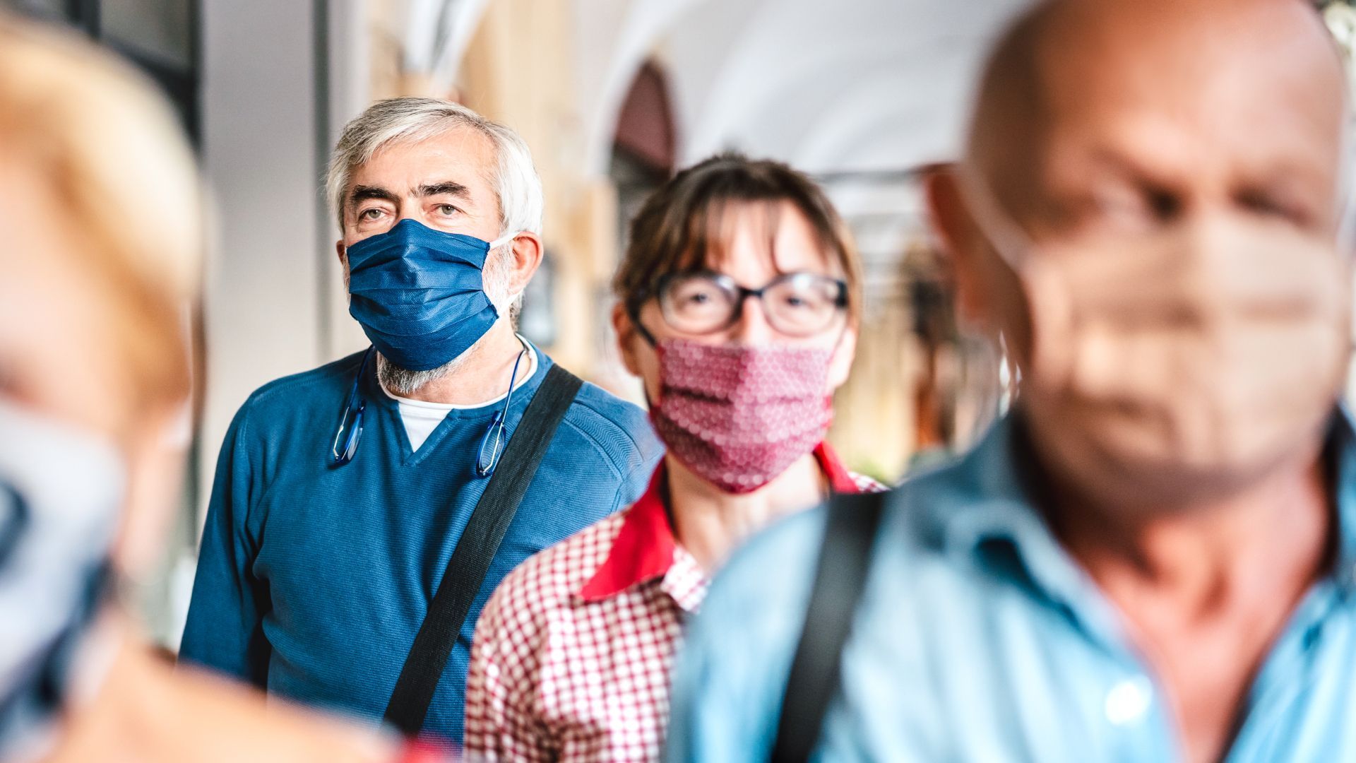 A group of people wearing face masks are standing in a line.