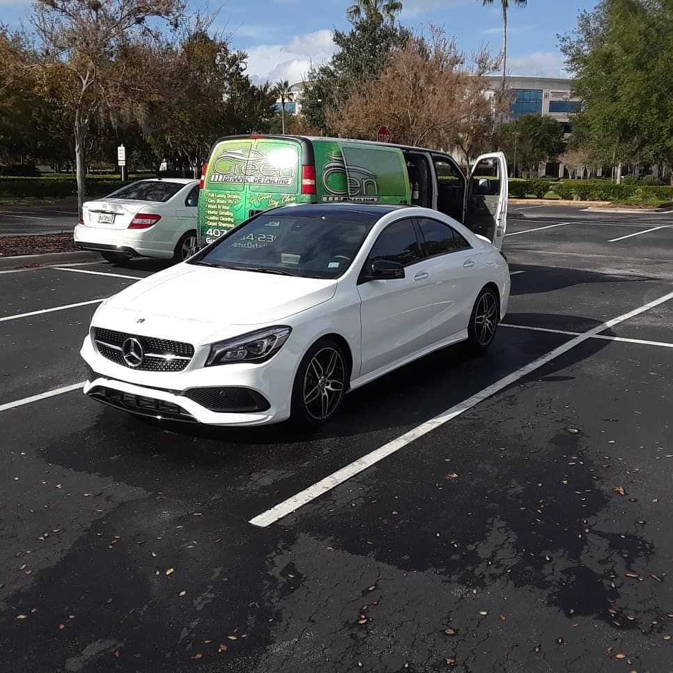 A white car is parked in a parking lot next to a green van