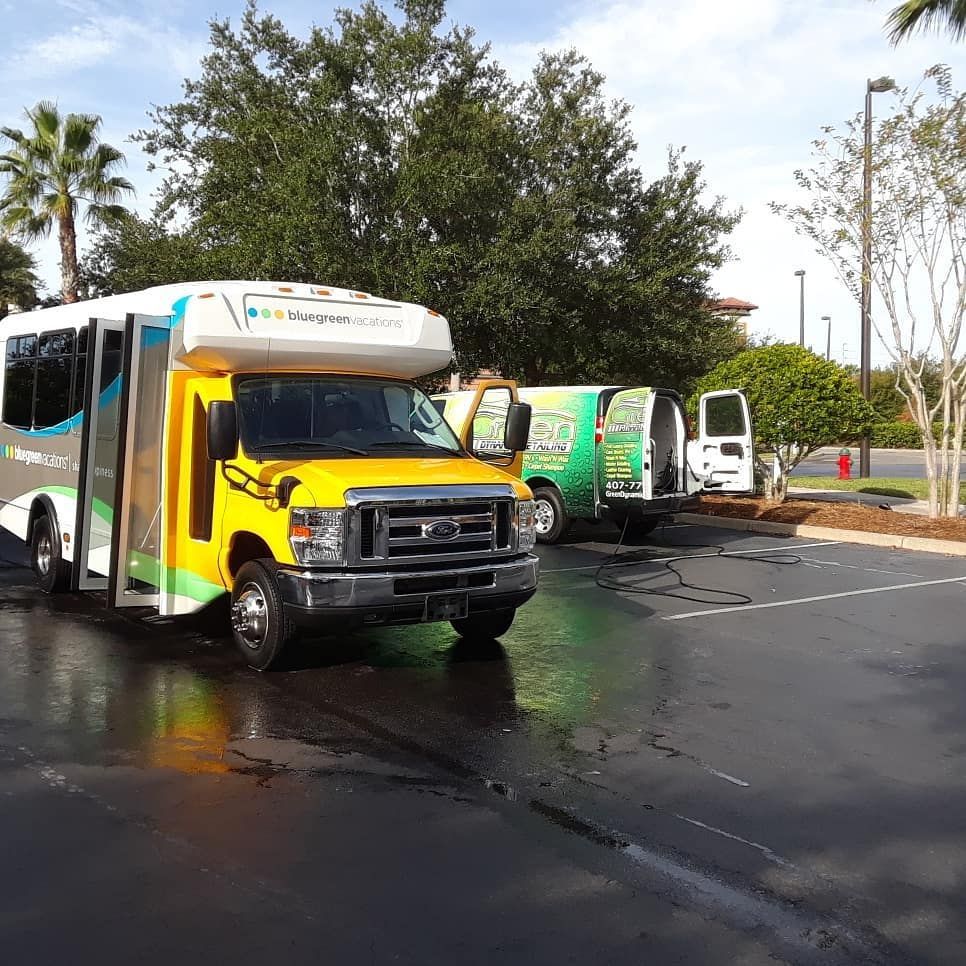 A yellow bus is parked next to a green van in a parking lot.
