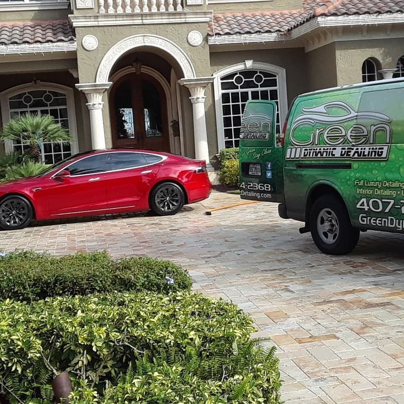 A red car is parked in front of a green van.