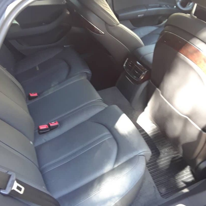 The back seat of a car with a red seat belt