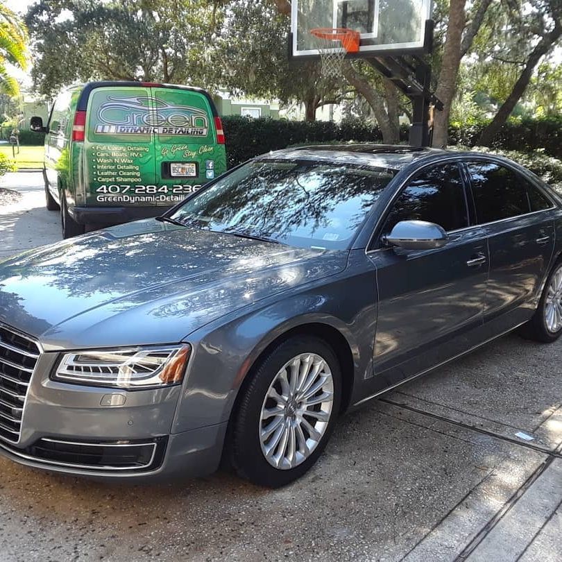 A gray car is parked in front of a basketball hoop