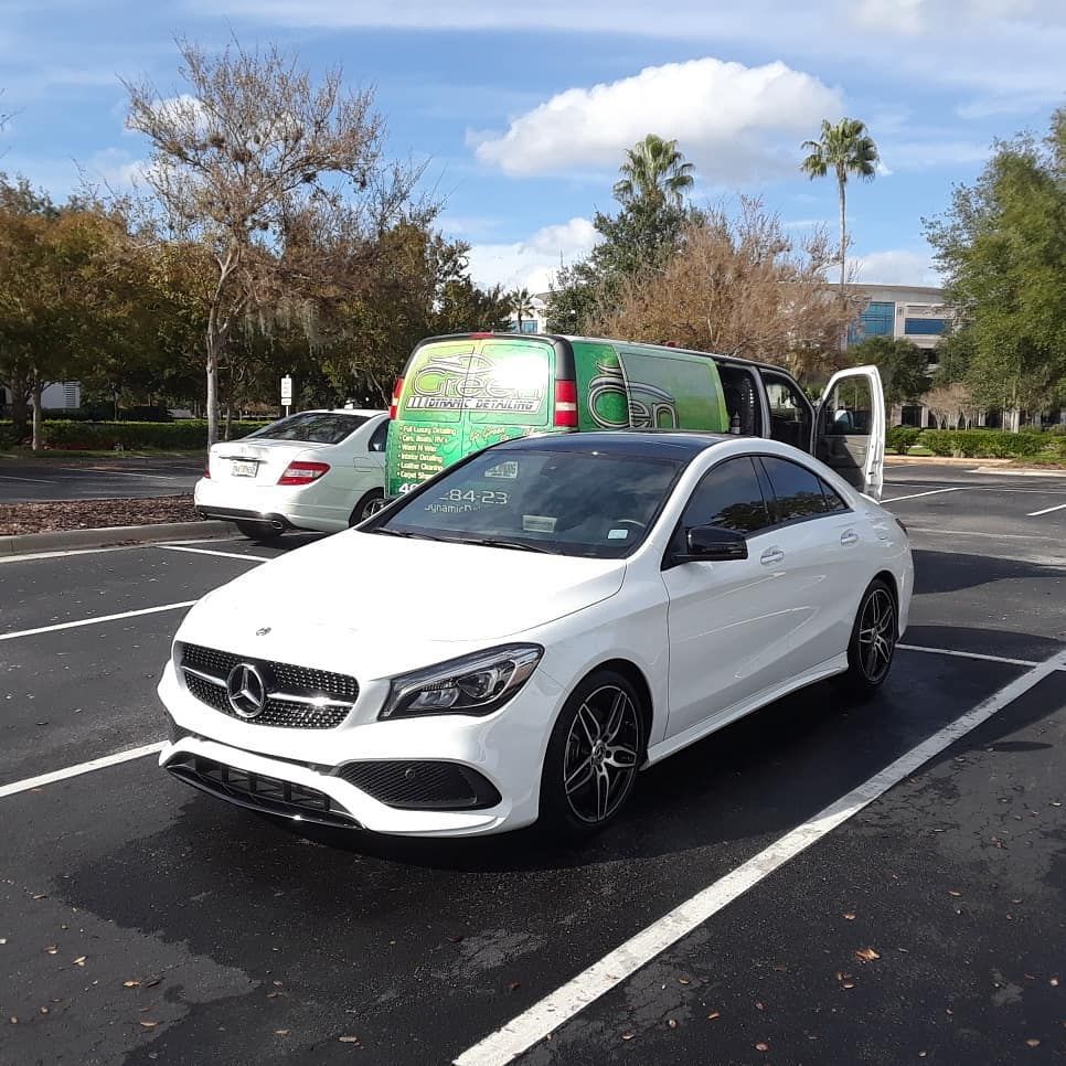 A white mercedes benz is parked in a parking lot