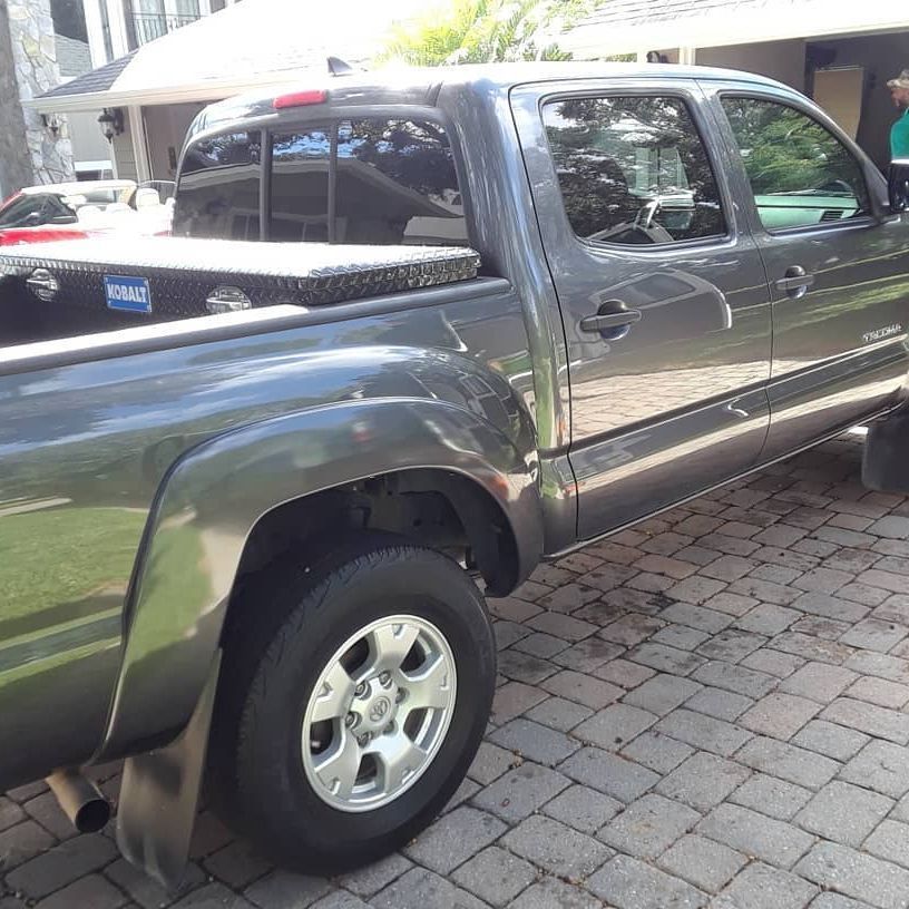 A black truck is parked on a brick driveway
