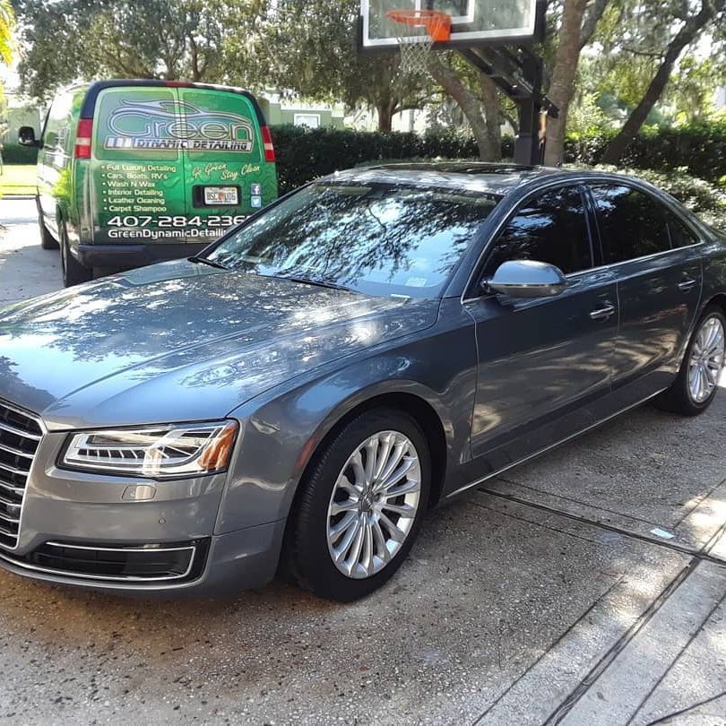 A gray car is parked in front of a basketball hoop