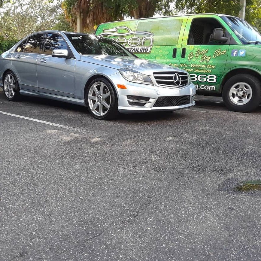 A silver car is parked next to a green van.
