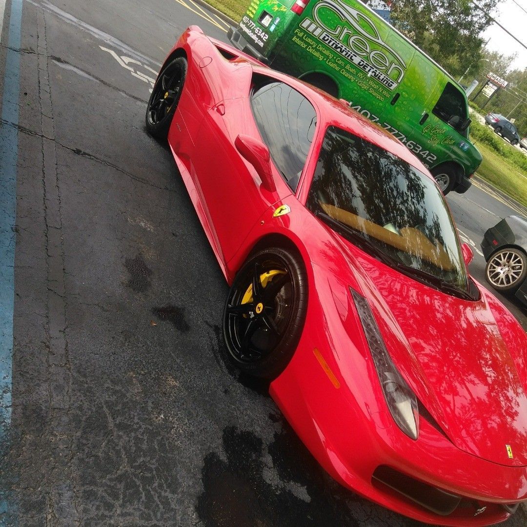 A red sports car is parked in a parking lot