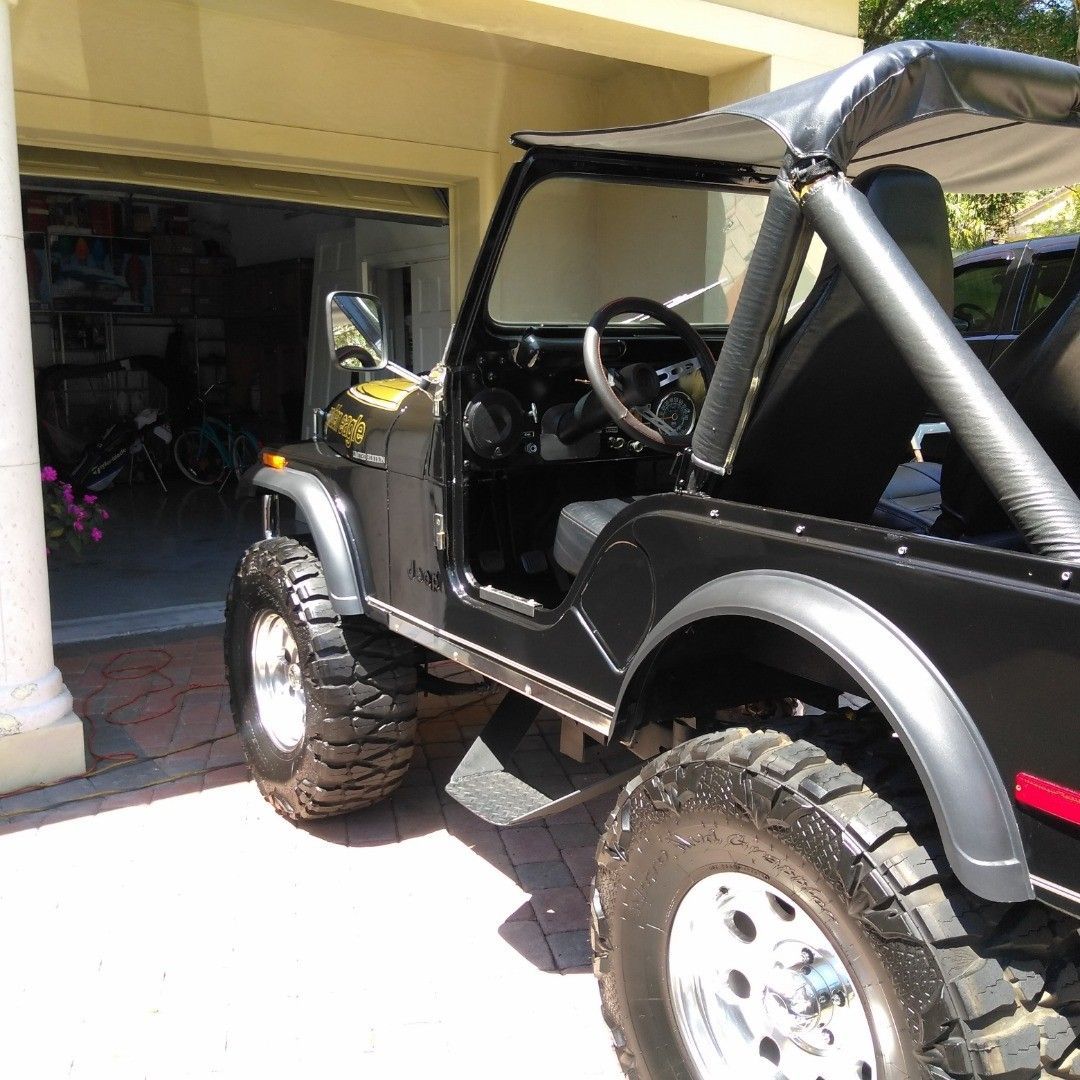 A black jeep is parked in front of a garage door