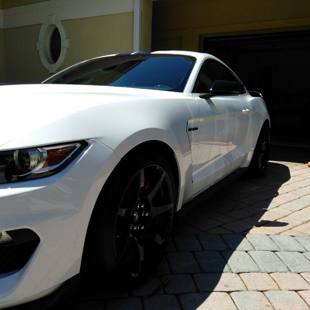 A white sports car is parked in front of a garage