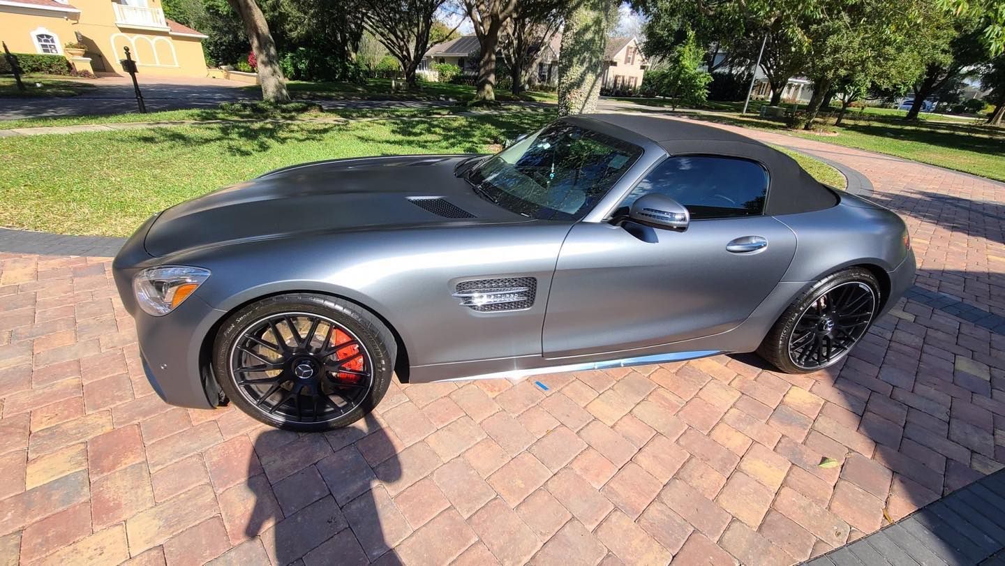 A mercedes benz amg gt convertible is parked on a brick driveway.