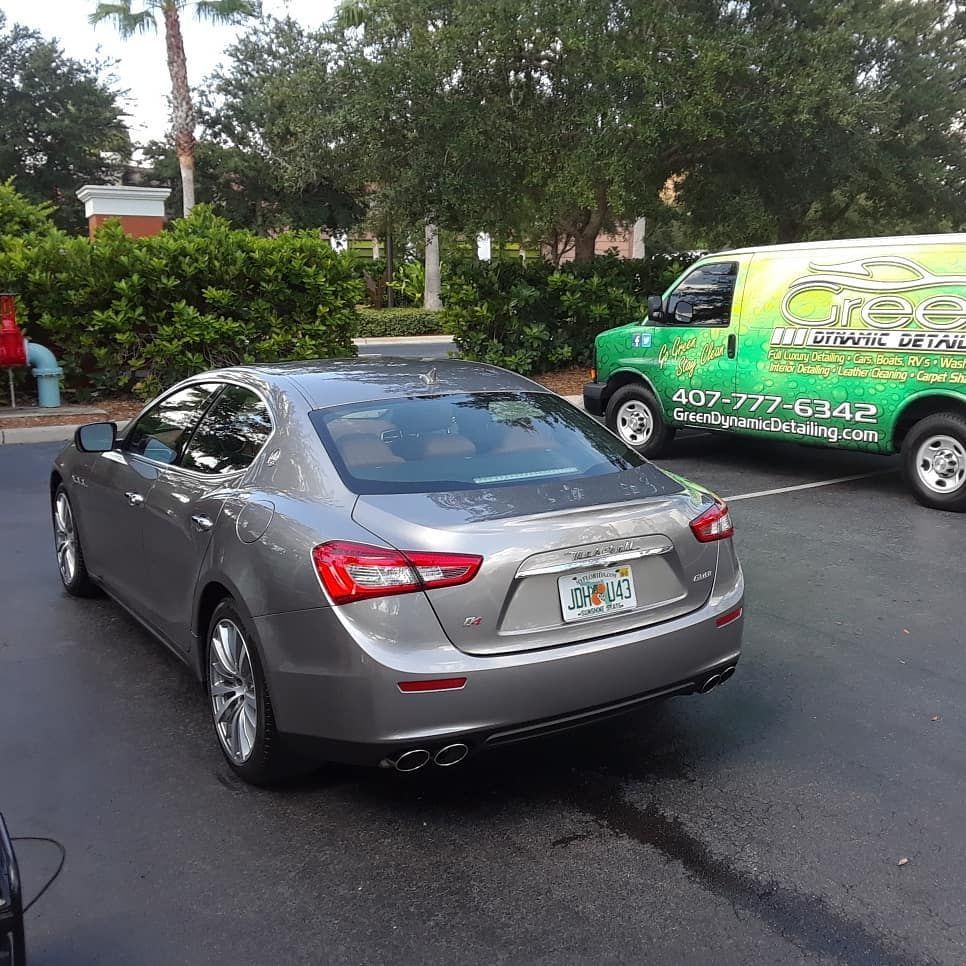 A silver car is parked next to a green van