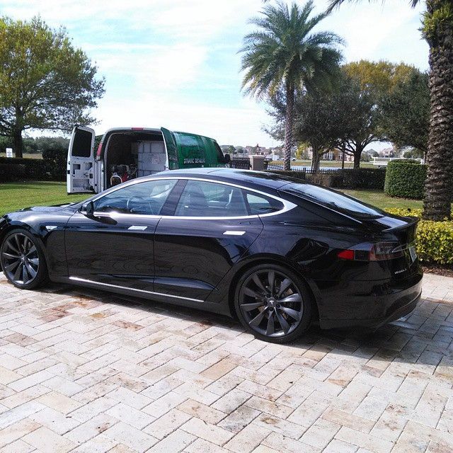 A black car is parked in front of a green van