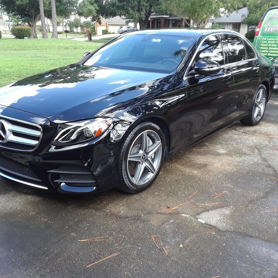 A black mercedes benz is parked in a driveway.