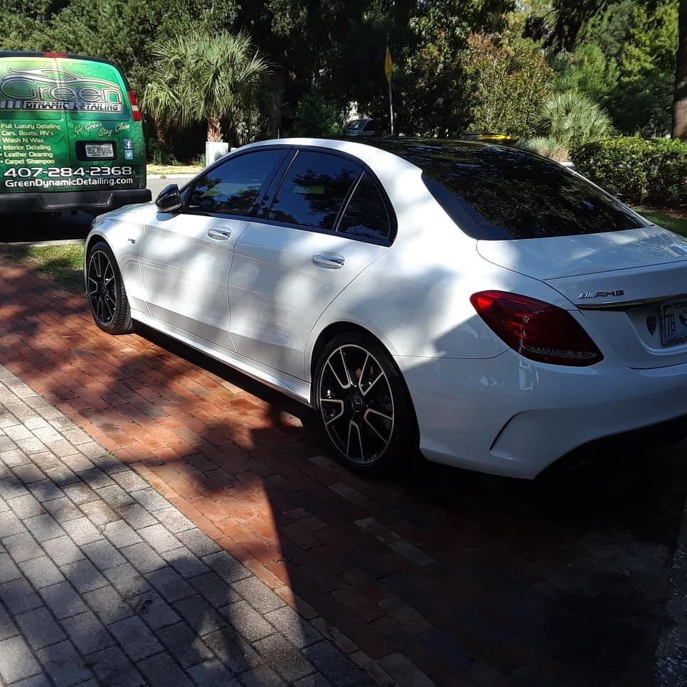 A white car is parked next to a green van
