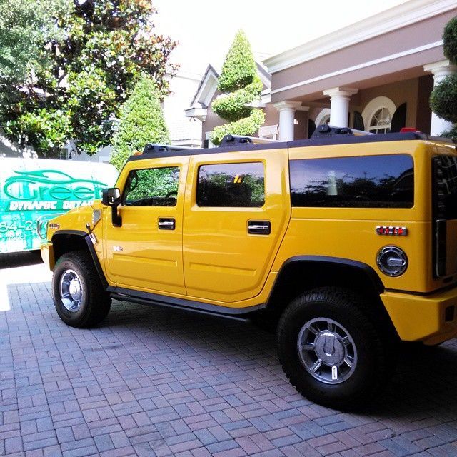 A yellow hummer is parked in front of a building that says green drive
