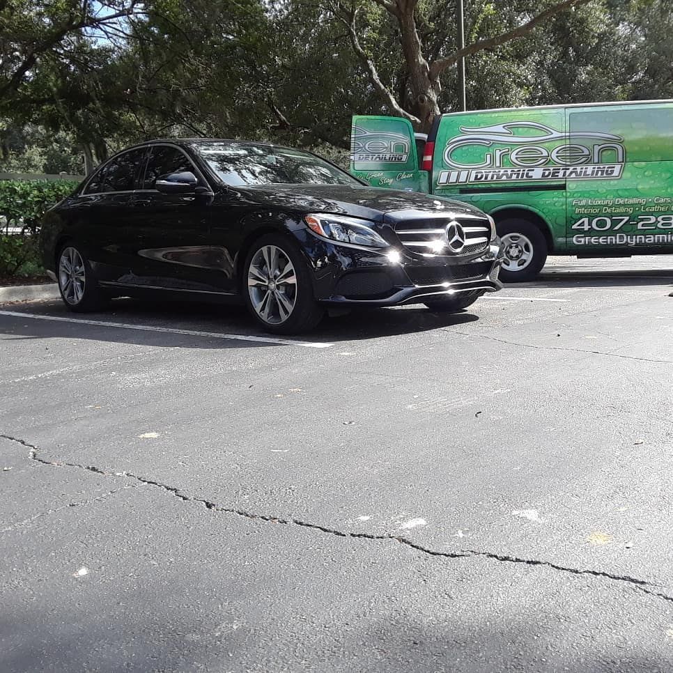 A black car is parked next to a green van that says green