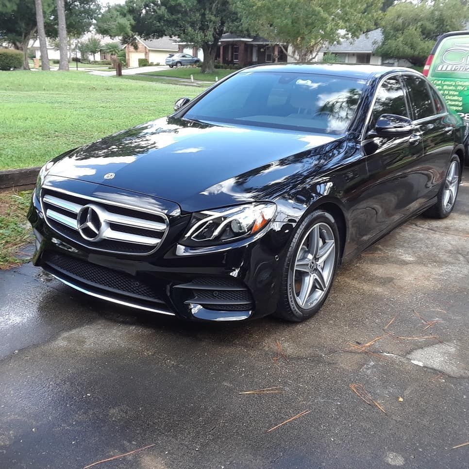 A black mercedes benz is parked in a driveway