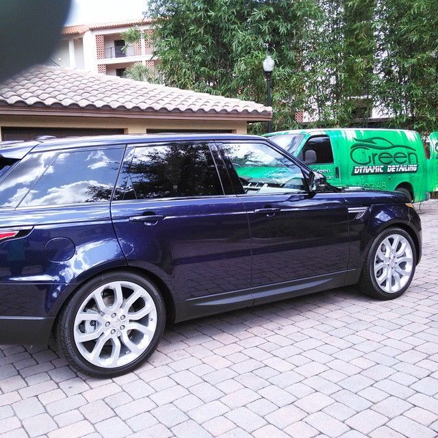 A blue car is parked in front of a green van that says green graphic detailing