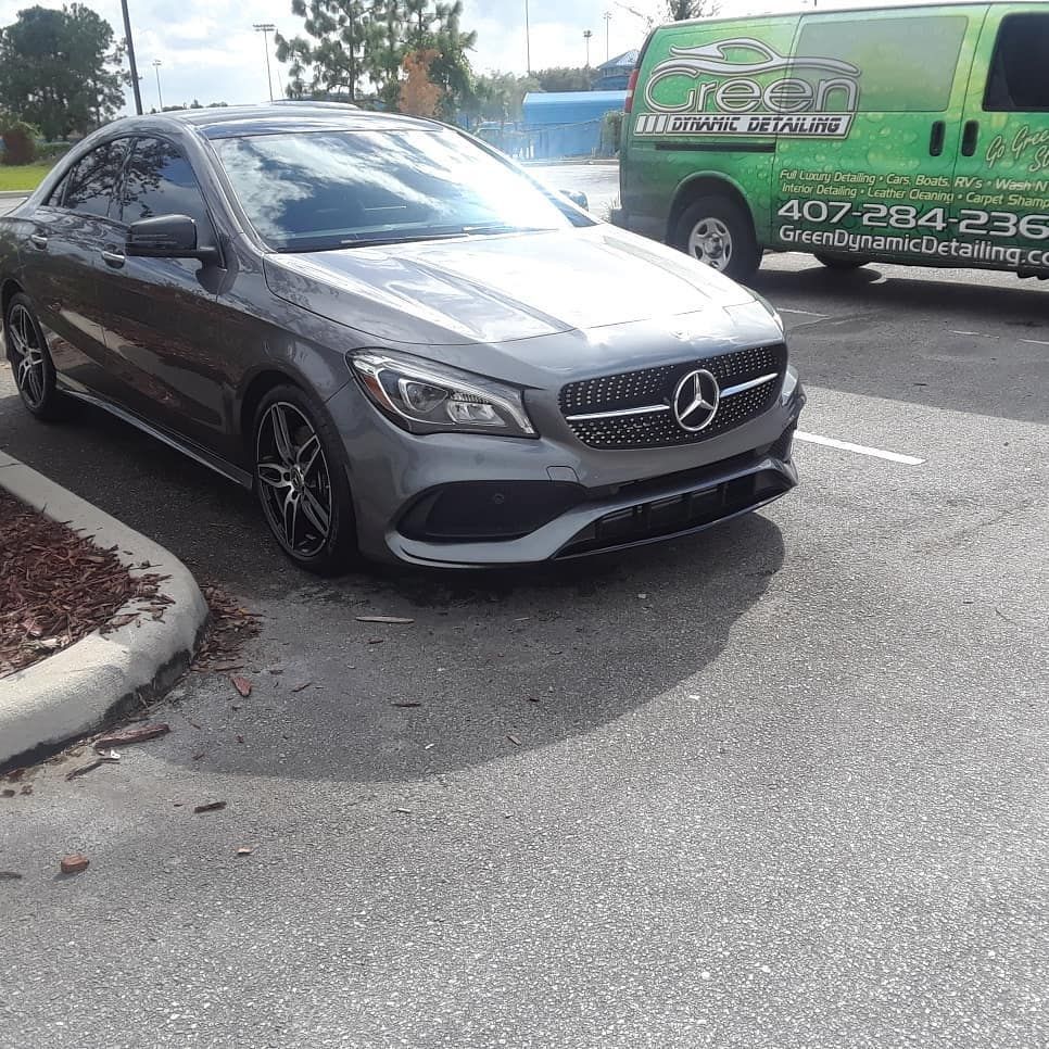 A mercedes benz cla class is parked in a parking lot next to a green van.