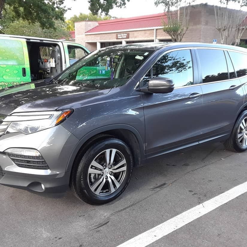 A gray suv is parked in a parking lot in front of a building.