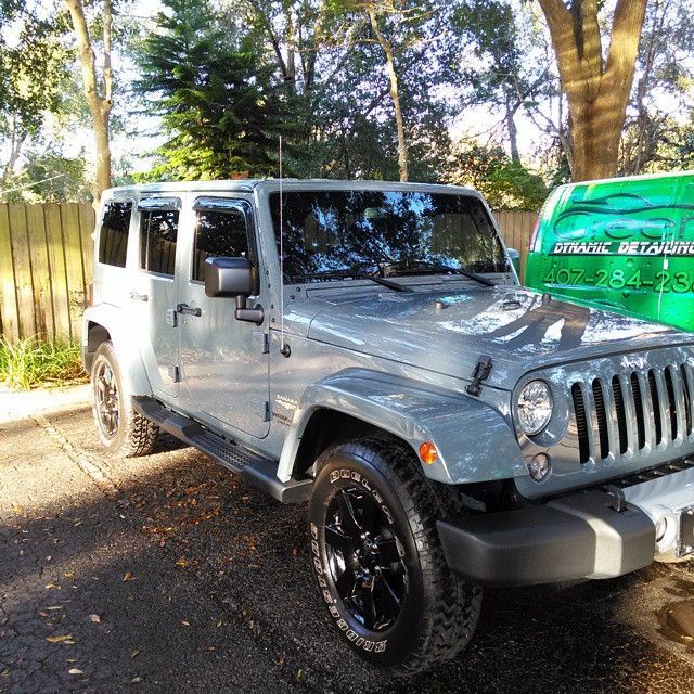 A grey jeep is parked next to a green van