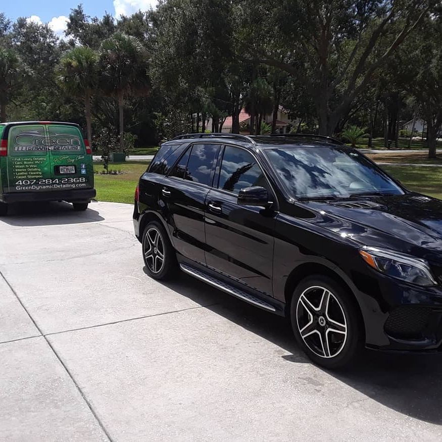 A gray car is parked in a parking lot next to a green van.