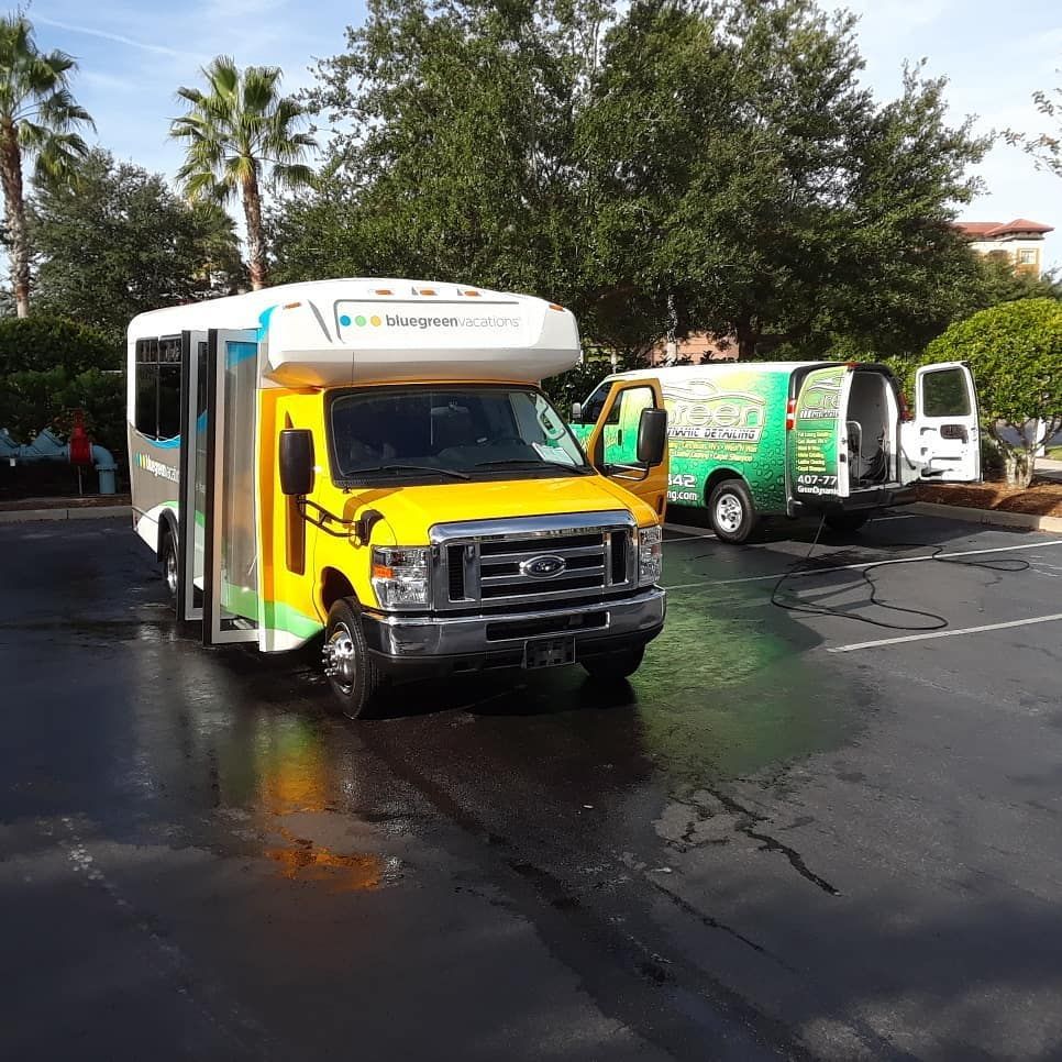 A yellow bus is parked next to a green van in a parking lot
