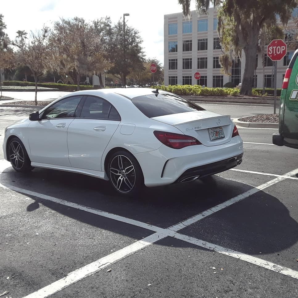 A white car is parked in a parking lot next to a stop sign