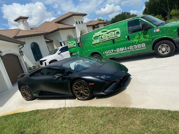 A gray car is parked in a parking lot next to a green van.