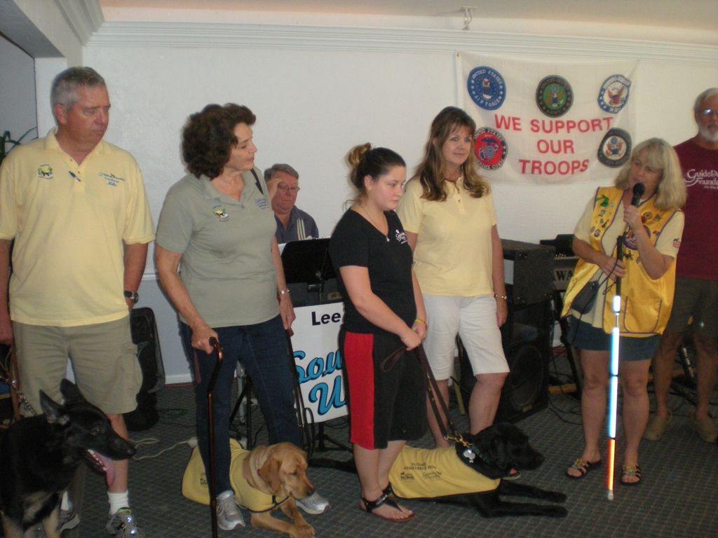 A group of people standing in front of a sign that says we support our troop