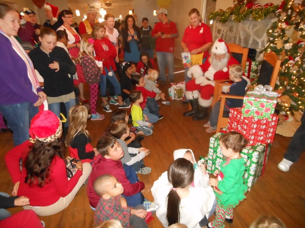 A group of children are sitting on the floor in front of santa claus