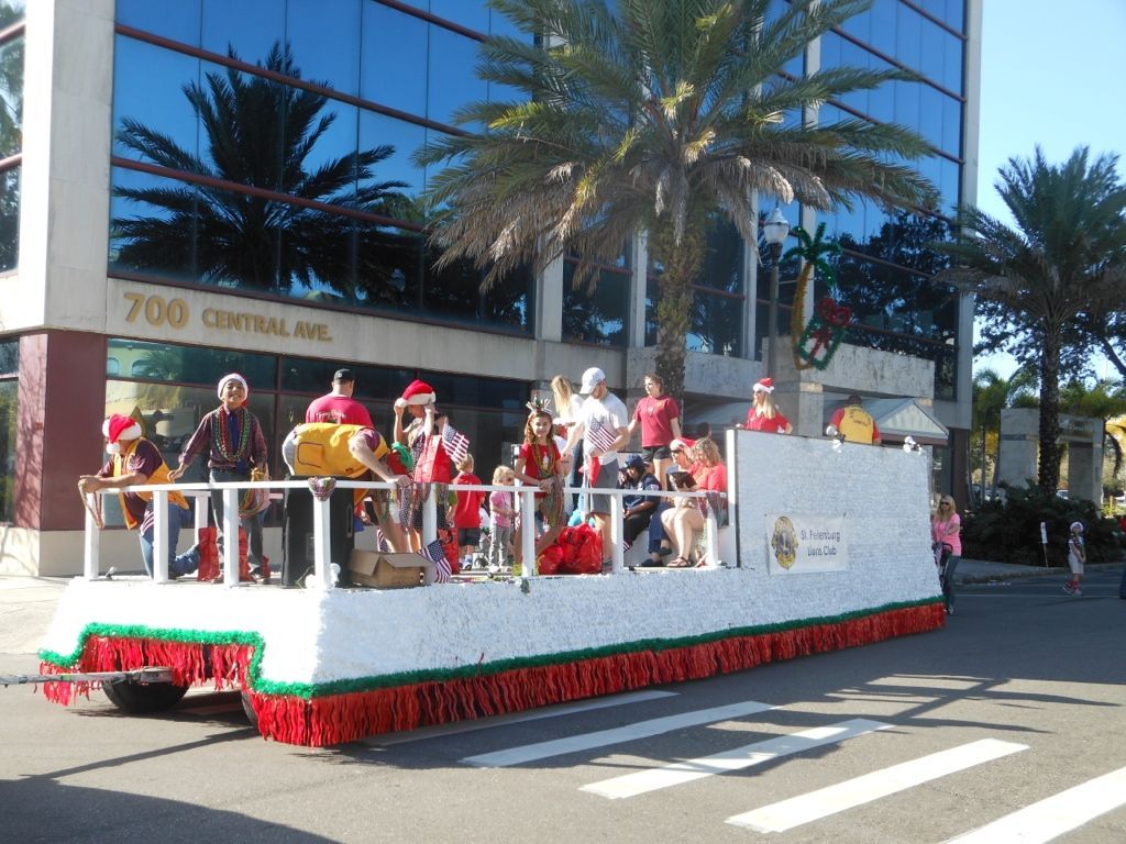 A christmas parade is taking place in front of a building with the number 700 on it