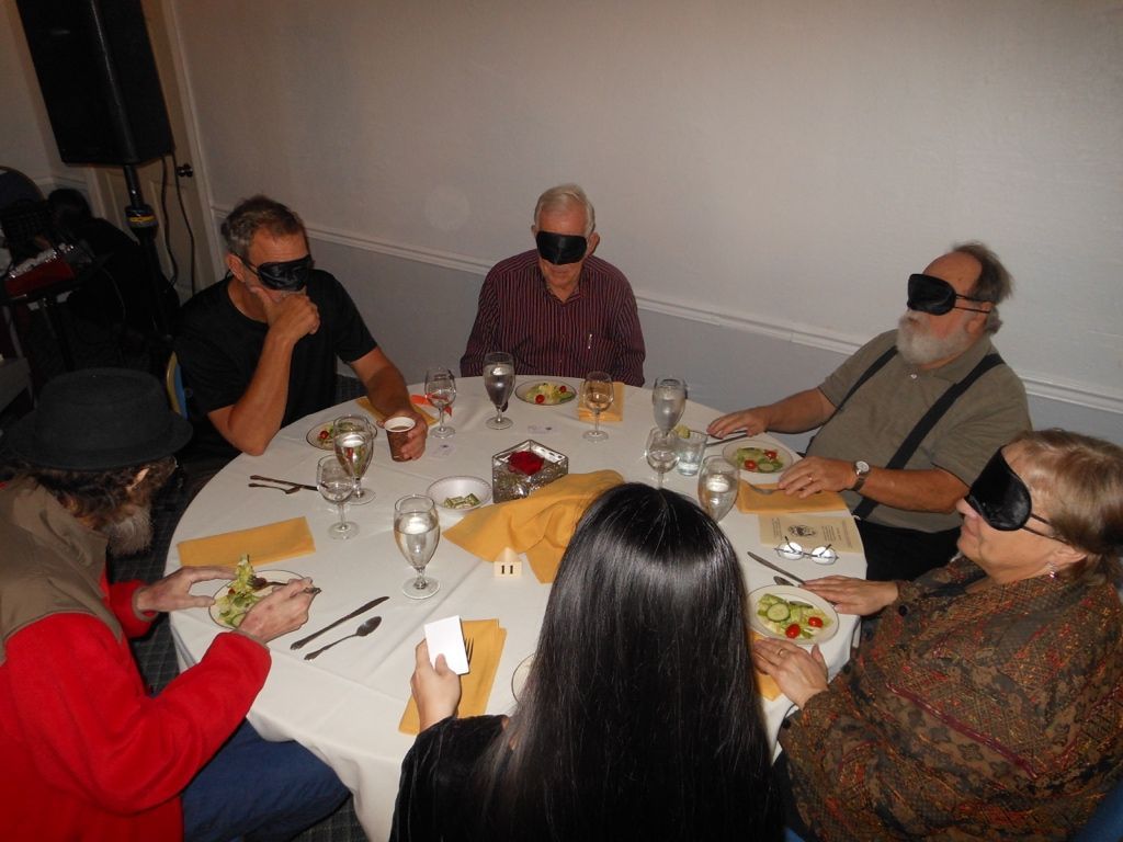 A group of people are sitting around a table wearing blindfolds