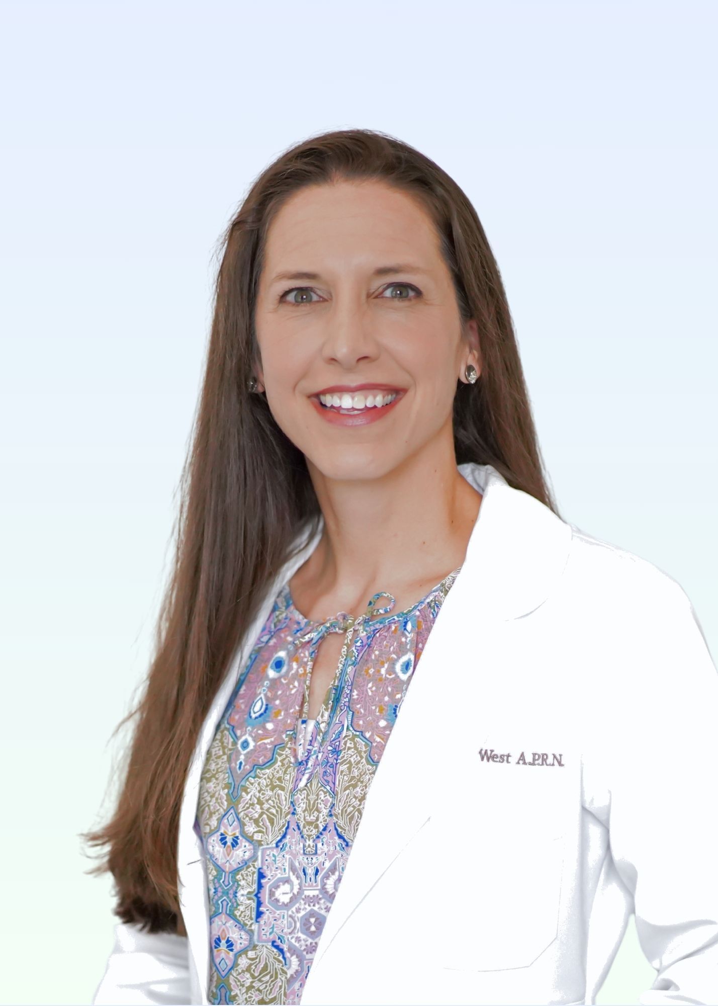 A woman in a white lab coat is smiling for the camera.