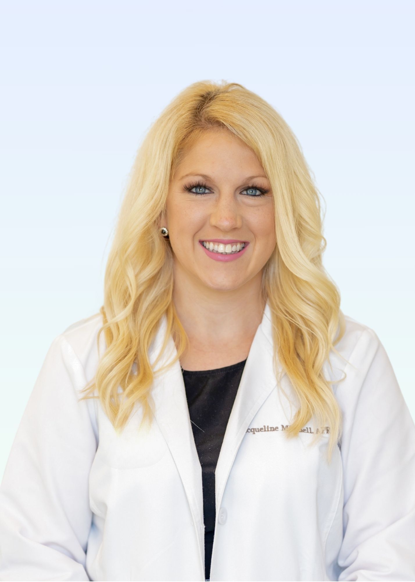 A woman in a white lab coat is smiling for the camera