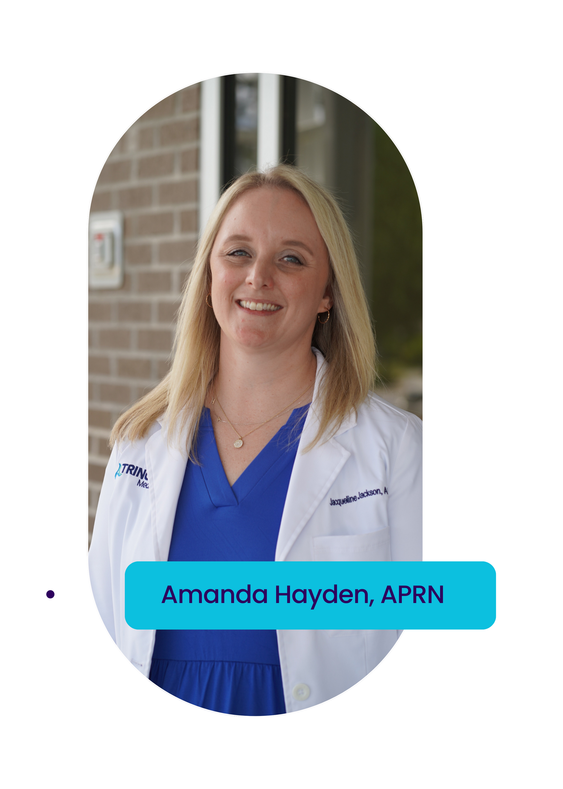 A woman in a white lab coat and blue shirt is smiling.