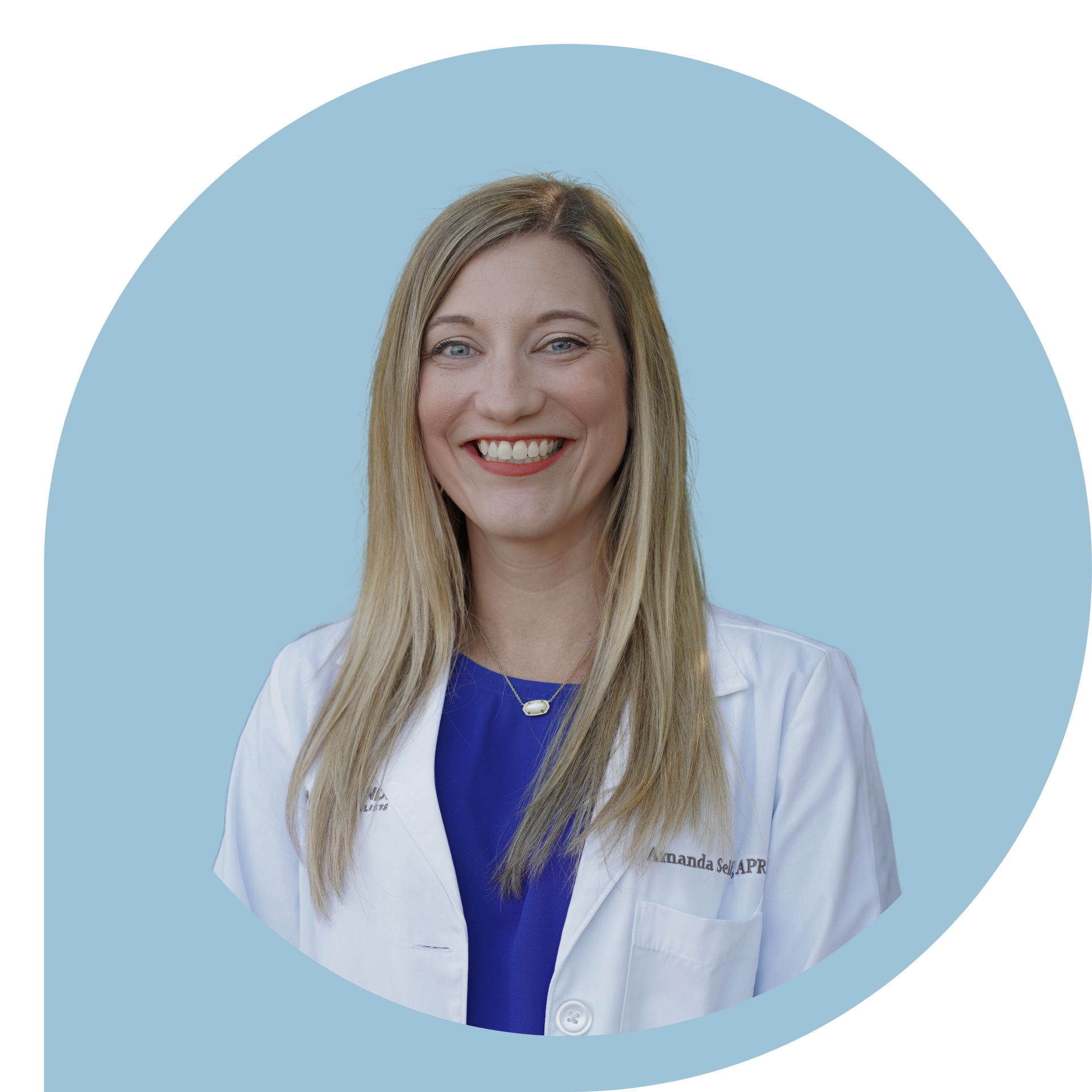 A woman in a white lab coat and blue shirt is smiling.