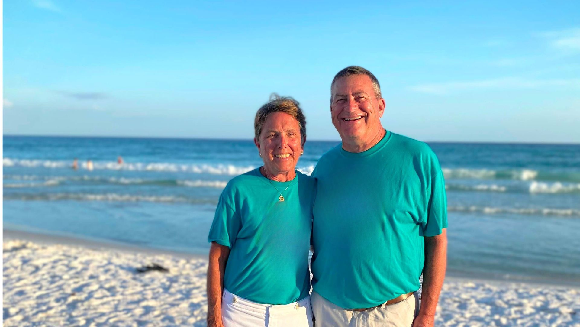 A man and a woman are posing for a picture on the beach.