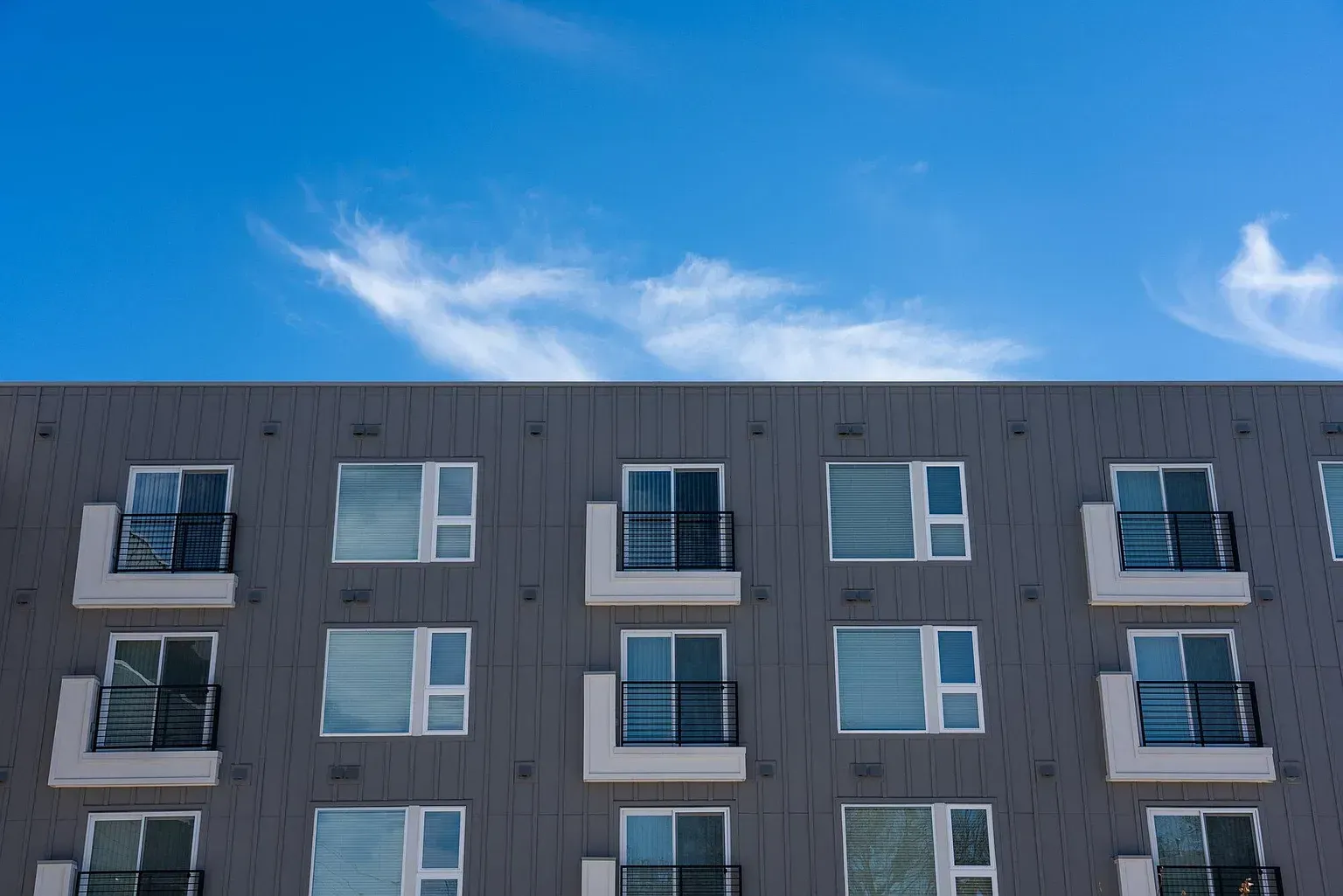 Exterior view of a modern apartment building with balconies under a clear blue sky.